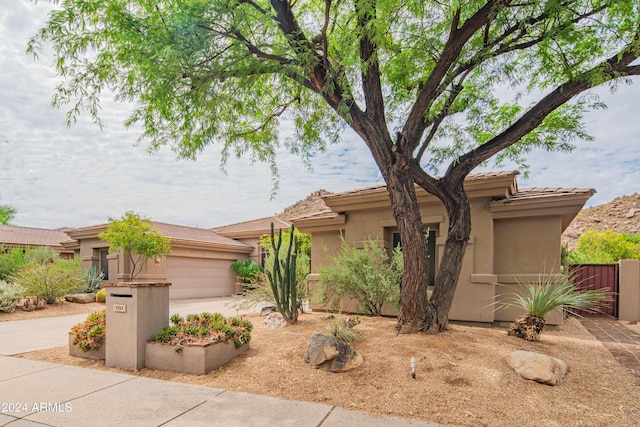 view of front of property featuring a garage, concrete driveway, fence, and stucco siding