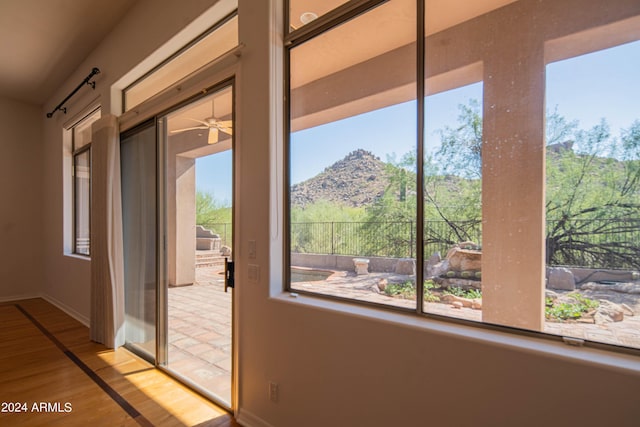 doorway featuring a ceiling fan, a mountain view, light wood-style flooring, and baseboards