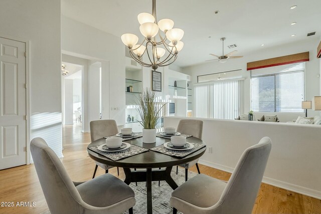 unfurnished living room with sink, light wood-type flooring, built in shelves, a fireplace, and ceiling fan with notable chandelier