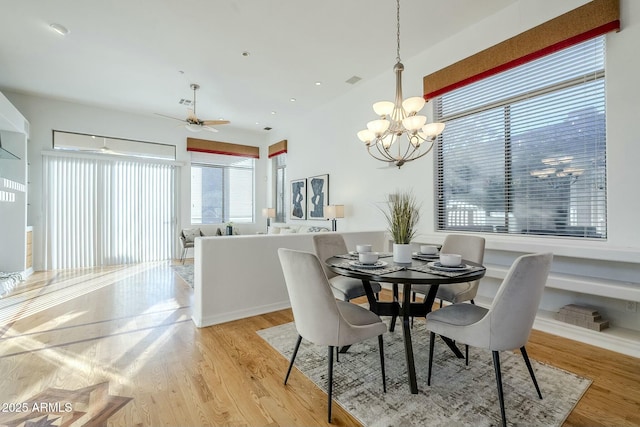 dining space with light wood-type flooring and ceiling fan with notable chandelier