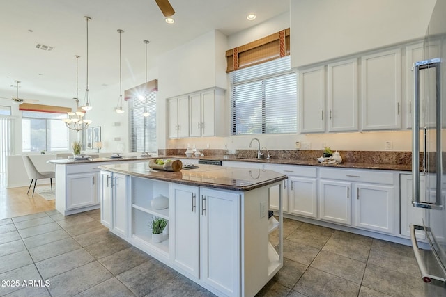 kitchen featuring a kitchen island, pendant lighting, white cabinetry, open shelves, and a sink