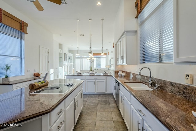 kitchen featuring dark stone counters, black electric stovetop, a sink, and white cabinetry