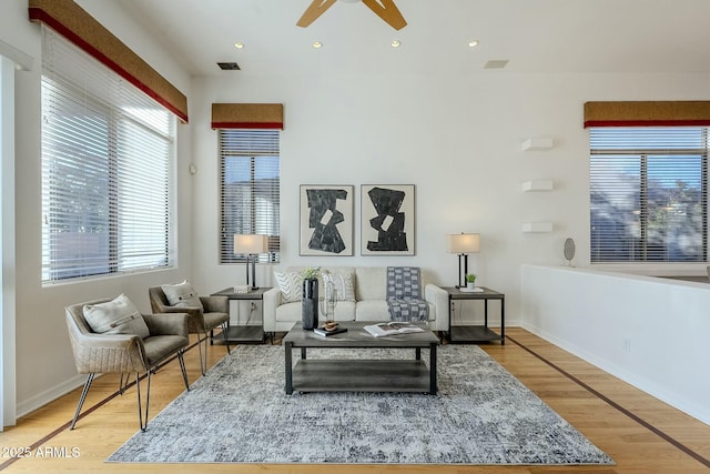 living room with a ceiling fan, visible vents, light wood-style flooring, and baseboards