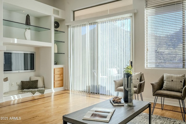 living room featuring wood finished floors, visible vents, and built in features