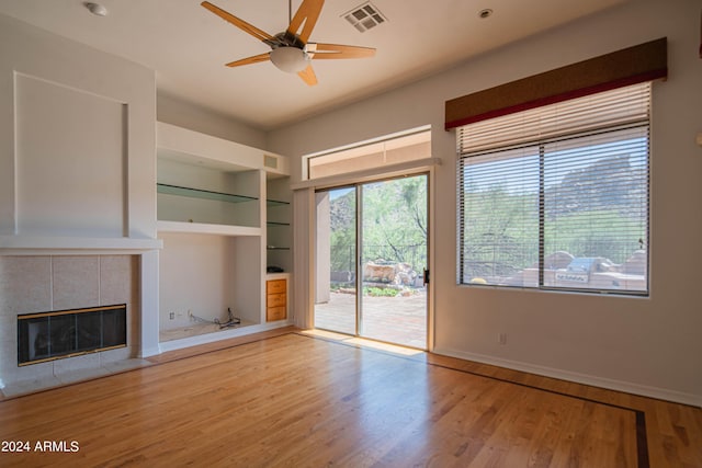 unfurnished living room with light wood-type flooring, a fireplace, visible vents, and built in features