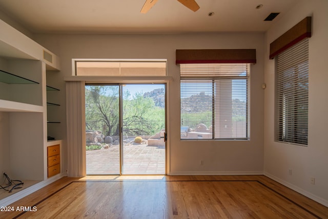 interior space featuring ceiling fan, visible vents, built in features, baseboards, and light wood finished floors