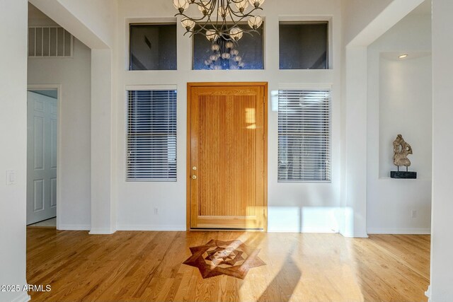 empty room with light hardwood / wood-style floors and ceiling fan with notable chandelier