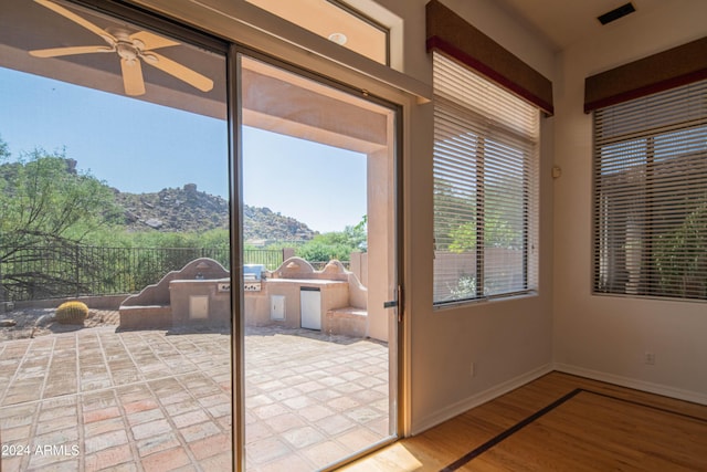 unfurnished sunroom featuring a ceiling fan, visible vents, and a mountain view