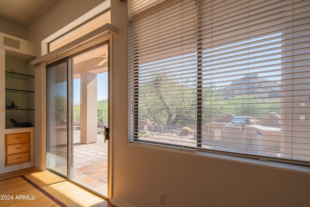 doorway to outside with light wood-type flooring, visible vents, and built in features