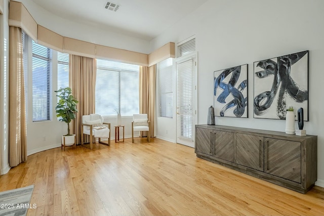 living area featuring light wood-type flooring, baseboards, and visible vents