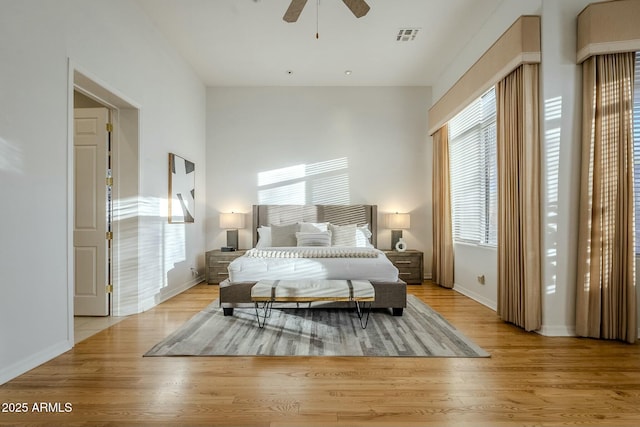 bedroom with light wood finished floors, visible vents, and baseboards