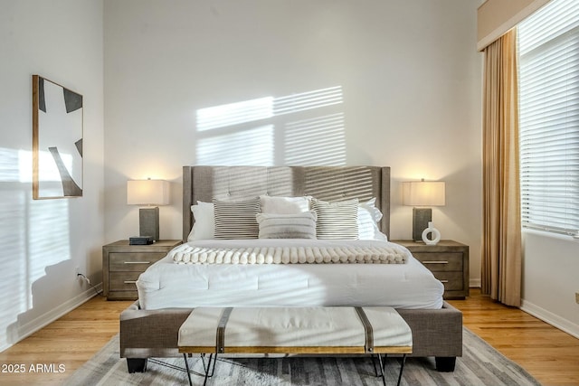 bedroom featuring multiple windows, light wood-style flooring, and baseboards