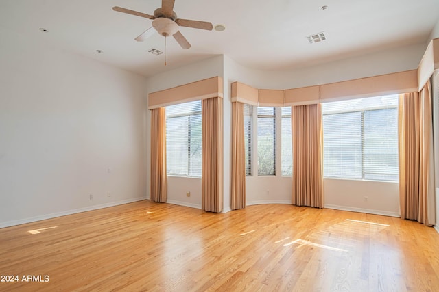 unfurnished room featuring light wood-style floors, a healthy amount of sunlight, and visible vents