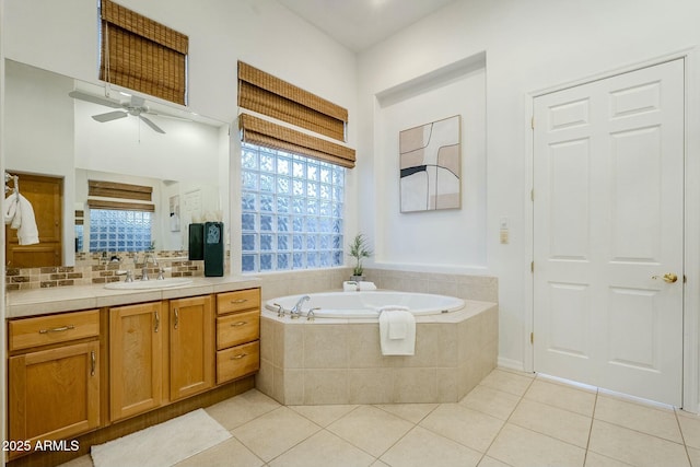 bathroom with a ceiling fan, vanity, a bath, tile patterned floors, and tasteful backsplash