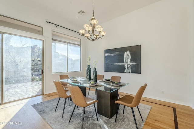 dining area with baseboards, visible vents, an inviting chandelier, and wood finished floors