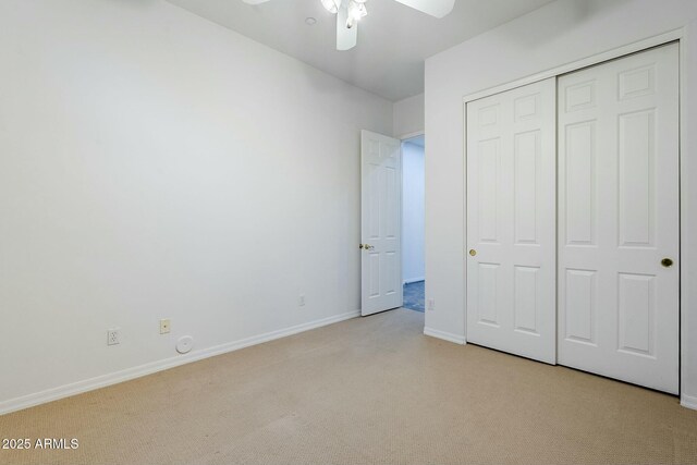 unfurnished bedroom featuring a closet, light colored carpet, ceiling fan, and baseboards