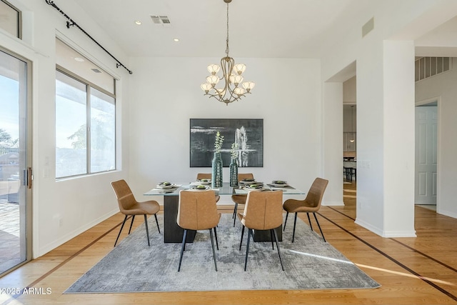 dining space with wood finished floors, visible vents, and an inviting chandelier