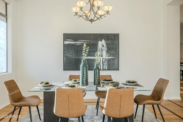 dining area with light wood-style flooring, baseboards, and an inviting chandelier