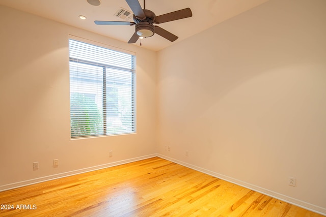 unfurnished room with ceiling fan, wood finished floors, visible vents, and baseboards