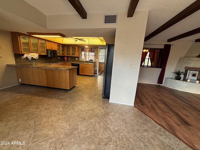 kitchen featuring beamed ceiling, a peninsula, black appliances, open floor plan, and brown cabinets