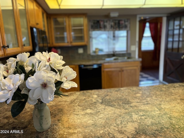 kitchen featuring glass insert cabinets, dishwasher, a sink, and brown cabinetry
