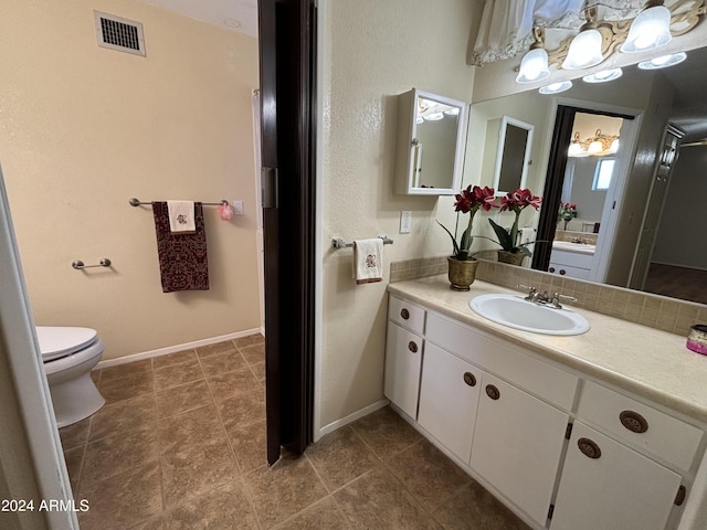 bathroom with toilet, visible vents, baseboards, and vanity