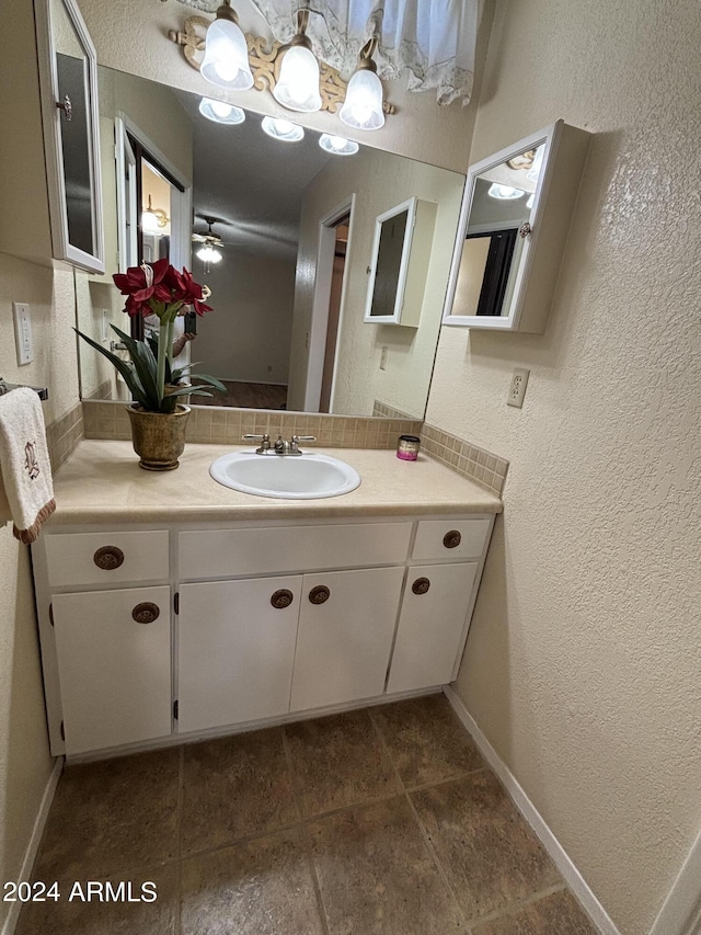 bathroom featuring a textured wall, vanity, and baseboards