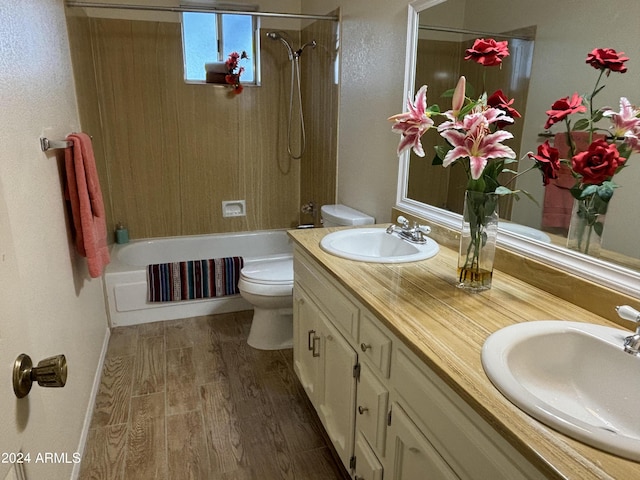 full bath with double vanity, a sink, toilet, and wood finished floors