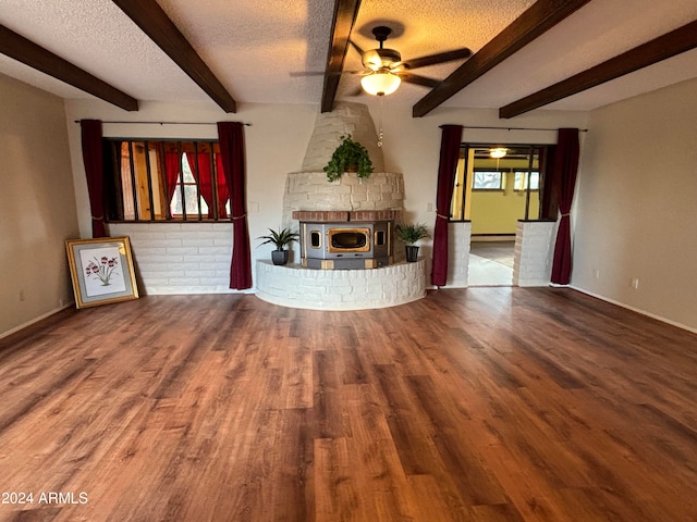 unfurnished living room featuring hardwood / wood-style flooring, a fireplace, beamed ceiling, ceiling fan, and a textured ceiling