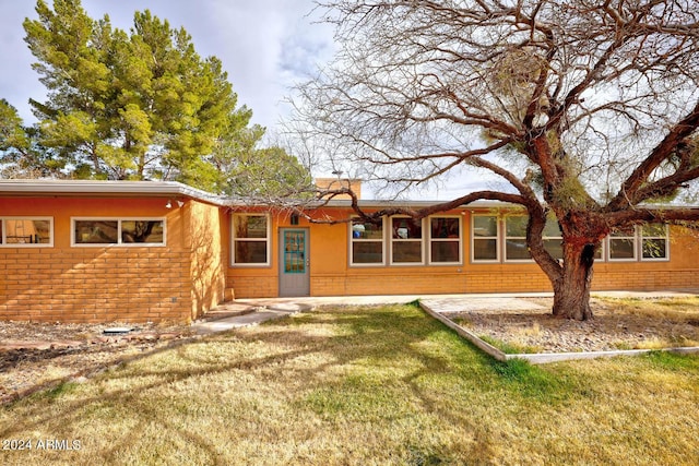 rear view of house with brick siding and a yard