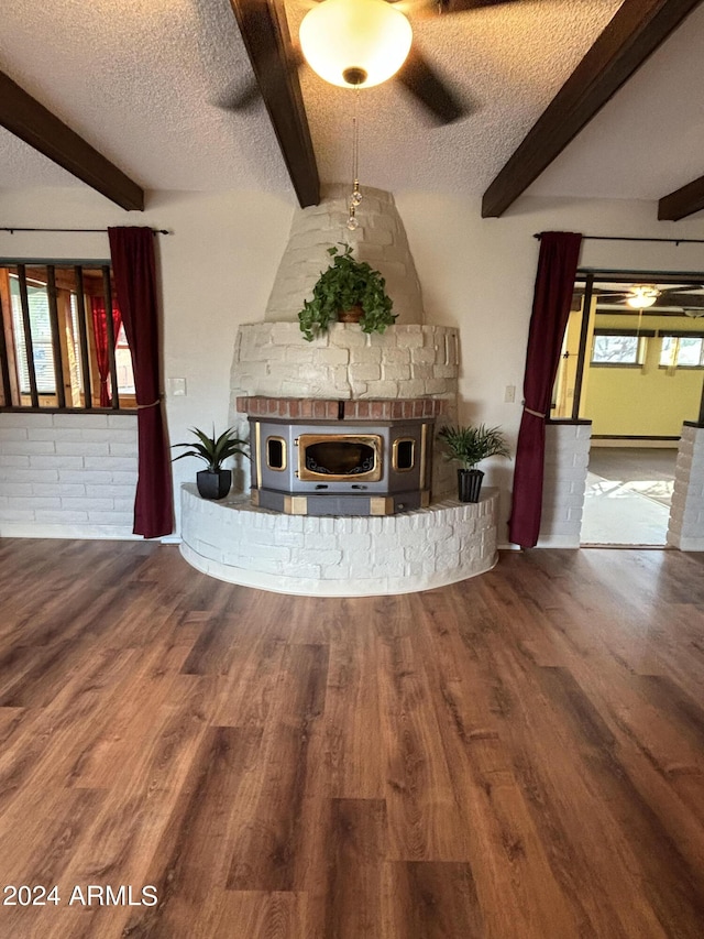 unfurnished living room featuring beam ceiling, a healthy amount of sunlight, wood finished floors, and a textured ceiling