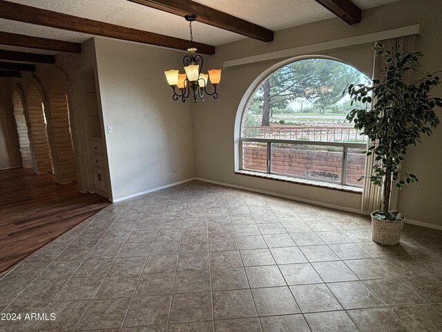 tiled empty room featuring beamed ceiling, baseboards, a notable chandelier, and a textured ceiling