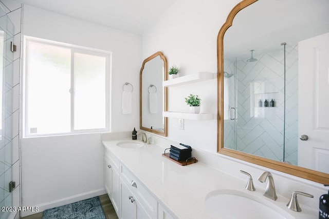 bathroom featuring double vanity, a shower stall, baseboards, and a sink