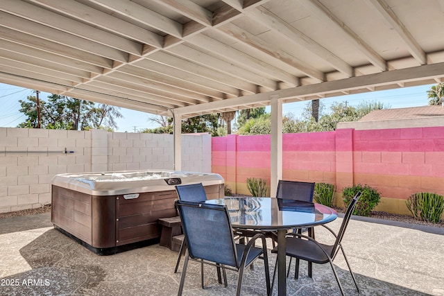 view of patio featuring outdoor dining space, a fenced backyard, and a hot tub