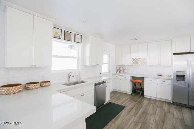 kitchen featuring appliances with stainless steel finishes, light countertops, a sink, and tasteful backsplash