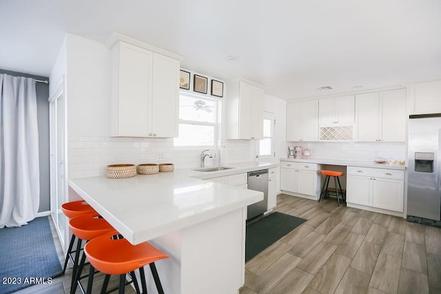 kitchen featuring stainless steel appliances, a sink, backsplash, and a kitchen bar