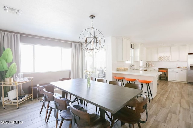 dining area featuring a chandelier, visible vents, and light wood-style floors