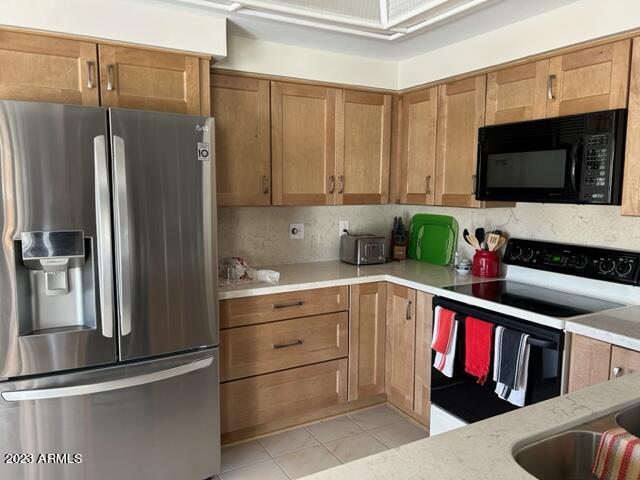 6122 E Saddleback St, Mesa, AZ 85215 - kitchen featuring brown cabinets, electric range, black microwave, stainless steel fridge, and light tile patterned floors