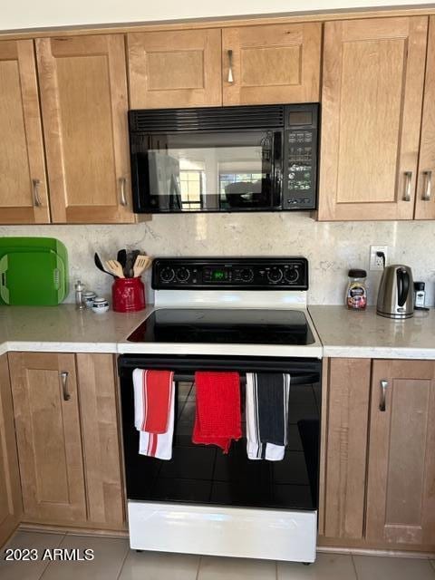 6122 E Saddleback St, Mesa, AZ 85215 - kitchen with backsplash, black microwave, electric range oven, light tile patterned floors, and light countertops