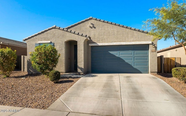 mediterranean / spanish house featuring stucco siding, a garage, concrete driveway, and fence