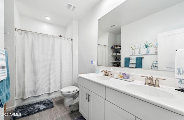 bathroom featuring double vanity, toilet, visible vents, and a sink