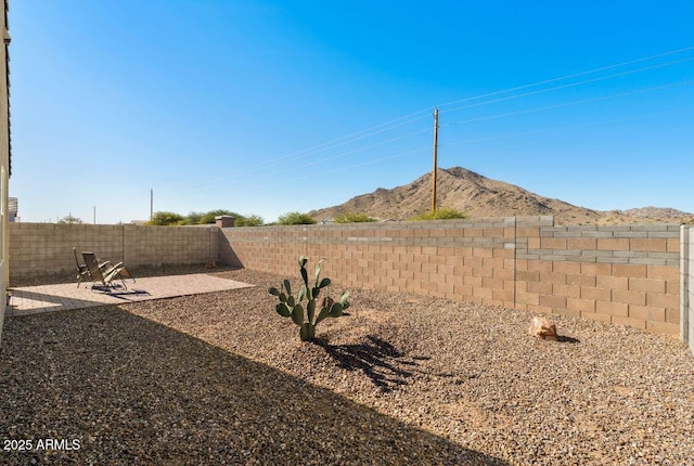 view of yard featuring a mountain view, a fenced backyard, and a patio