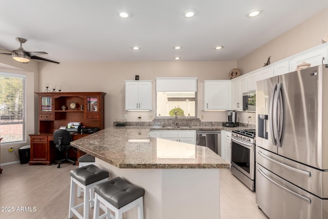 kitchen featuring light stone countertops, stainless steel appliances, a kitchen breakfast bar, and white cabinets