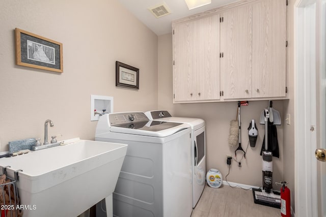 washroom featuring sink, light hardwood / wood-style floors, cabinets, and independent washer and dryer