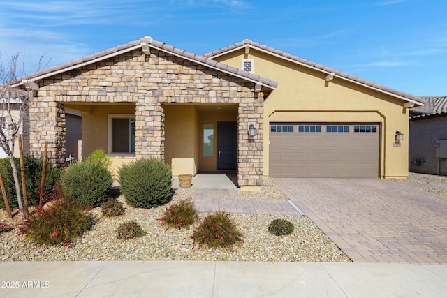 view of front of home with a tiled roof, stucco siding, an attached garage, and decorative driveway