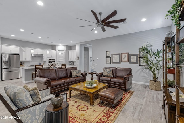living area featuring recessed lighting, baseboards, light wood-type flooring, and a ceiling fan