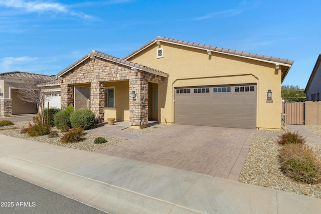 view of front of property with stucco siding, driveway, an attached garage, and a gate