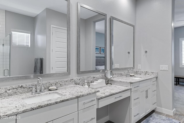 bathroom featuring wood finished floors, two vanities, baseboards, and a sink