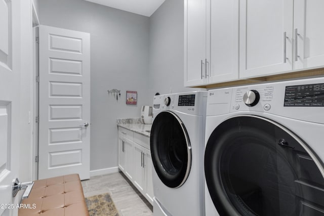 washroom with cabinet space, washing machine and dryer, and baseboards