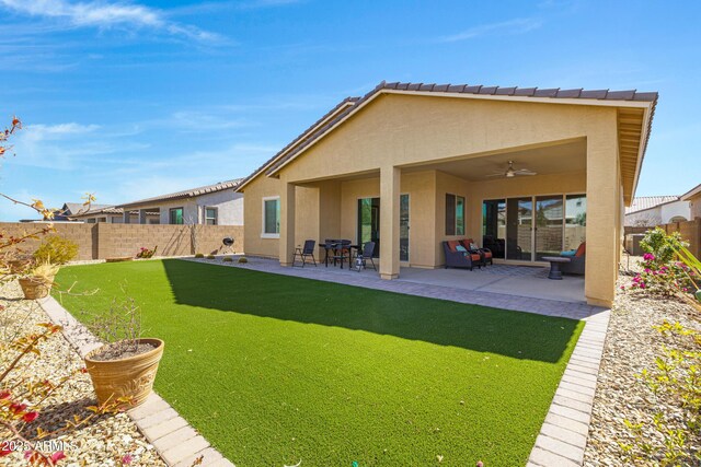 rear view of property with a patio, a ceiling fan, a yard, a fenced backyard, and stucco siding